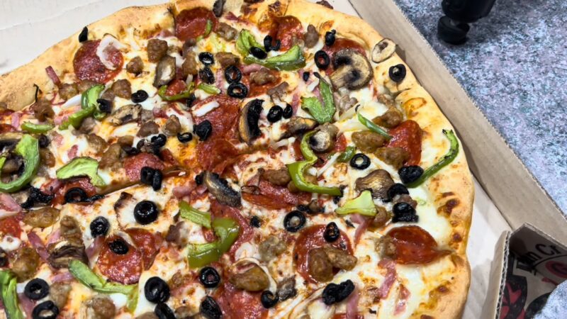 Close-up of a Supreme Pizza topped with pepperoni, green peppers, black olives, mushrooms, and sausage