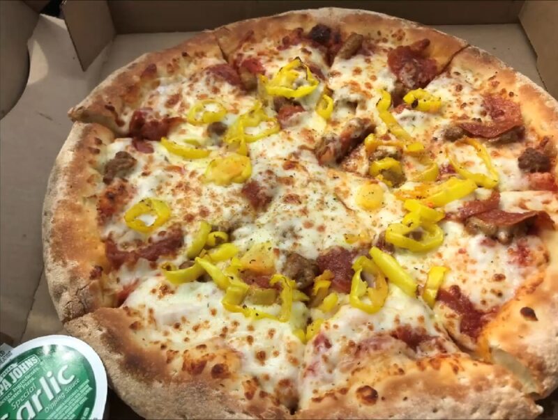 A pizza topped with vibrant banana peppers, Italian sausage, and pepperoni