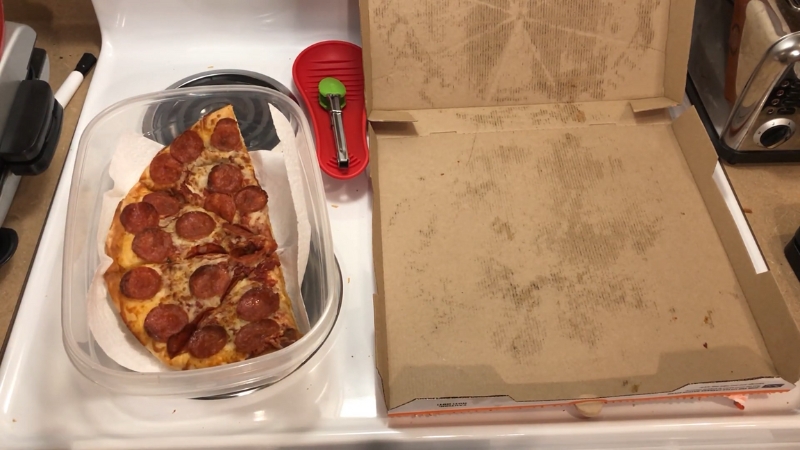 A Slice of Pepperoni Pizza Stored in A Container Next to An Empty Pizza Box