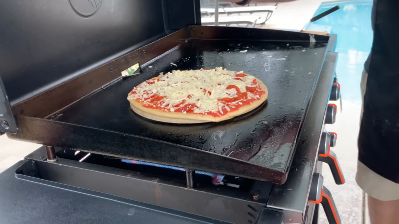 A Pizza with Sauce, Cheese, and Pepperoni Is Cooking on A Blackstone Griddle, Showcasing a Homemade Pizza Recipe in Progress