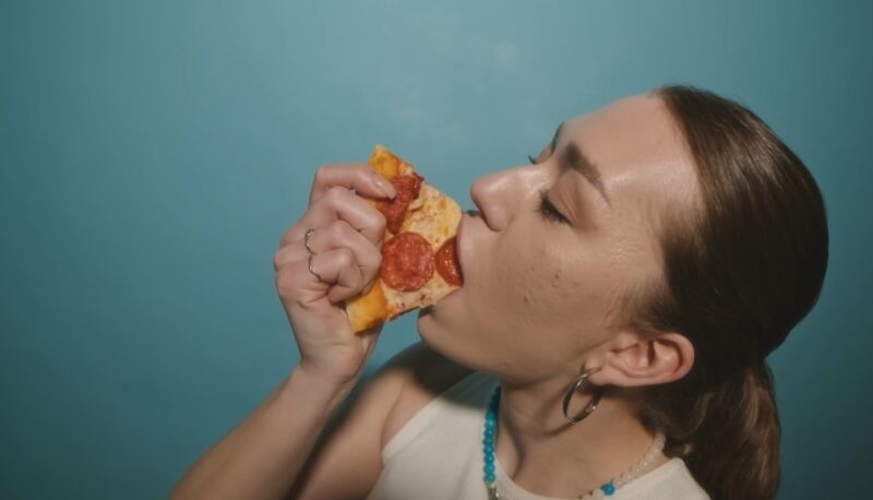 A close-up of a person savoring a slice of pepperoni pizza