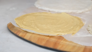 A Raw Gluten-Free Pizza Crust on Parchment Paper, Placed on A Wooden Pizza Peel, Ready for Pre-Baking