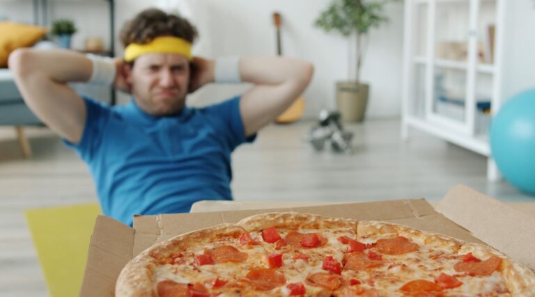 A man performs abdominal exercises while a pizza sits nearby