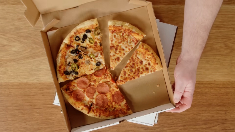 An Open Pizza Box with A Few Leftover Slices of Different Toppings on A Wooden Table